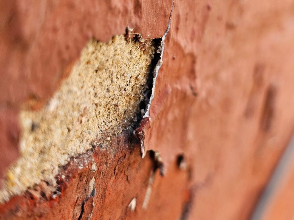 Masonry facade showing peeling and flaking paint damage