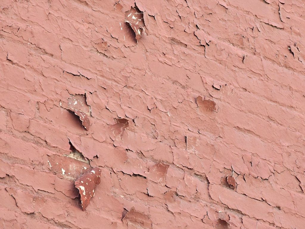Masonry wall with peeling paint and damaged mortar joints