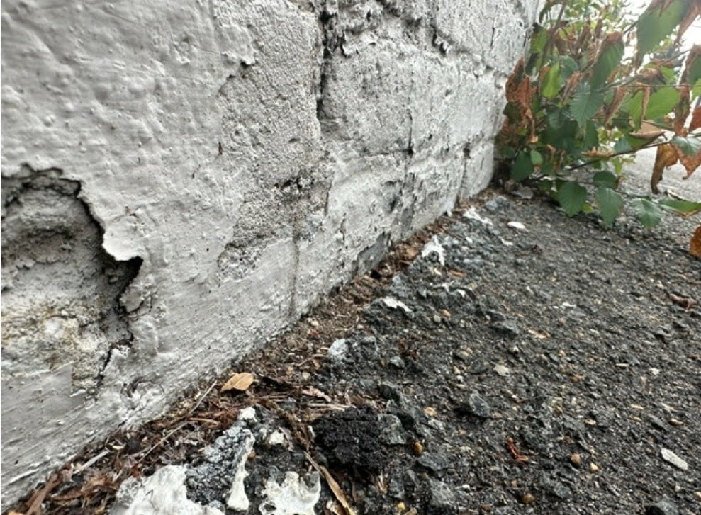 Close-up view of open asphalt to brick wall joint construction detail