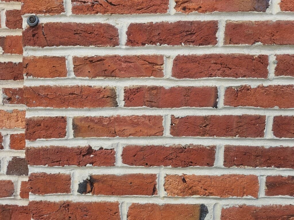 Masonry contractor applying concave mortar joints during brick pointing